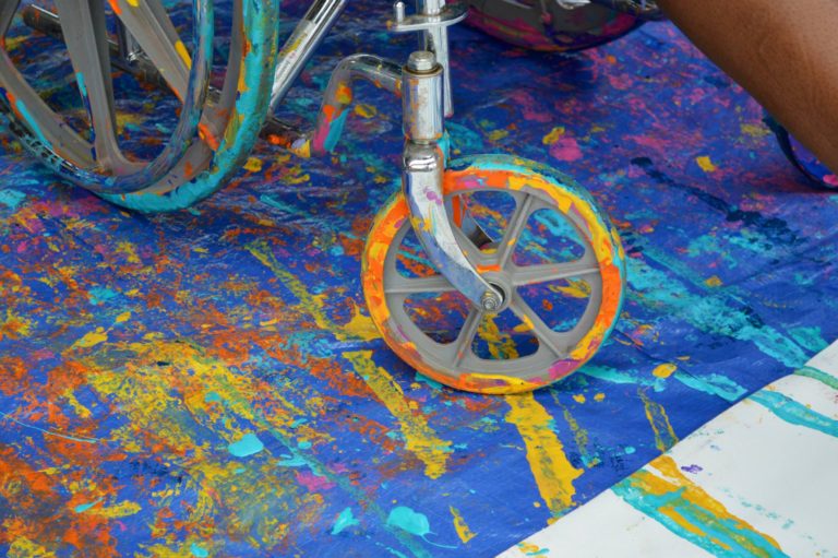 The wheels of a wheelchair covered in paint.