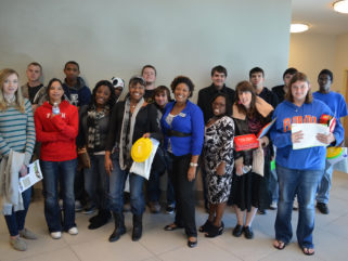 A group of youth smile for a picture in a hallway.